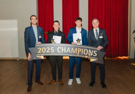 Vier Personen posieren mit einer Auszeichnung für die 2025 Champions in einem Innenraum.