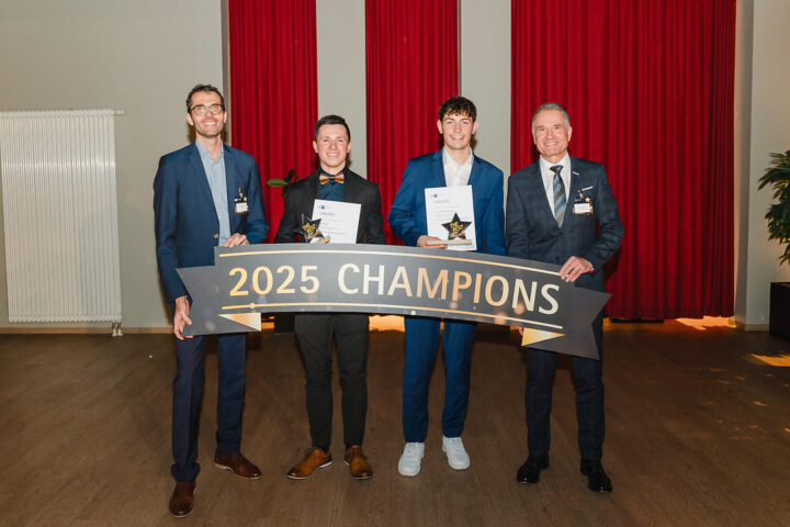 Vier Personen posieren mit einer Auszeichnung für die 2025 Champions in einem Innenraum.