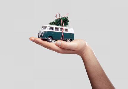 Ein handgehaltenes Modell eines Volkswagen Bulli mit einer kleinen Weihnachtsdekoration auf dem Dach.