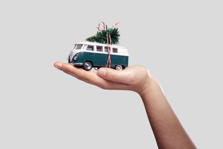 Ein handgehaltenes Modell eines Volkswagen Bulli mit einer kleinen Weihnachtsdekoration auf dem Dach.